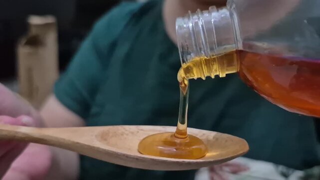 pure honey being poured from a clear plastic bottle onto a wooden spoon