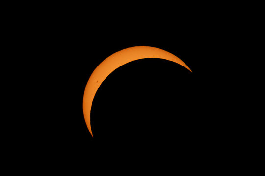 Aerial view of a partial solar eclipse with the sun appearing as a bright crescent against the dark sky over Mulhouse, Grand Est, France.