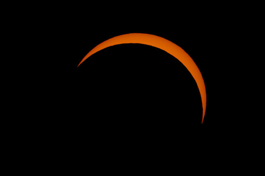 Aerial view of a partial solar eclipse showing the sun as a glowing crescent against the dark sky Mulhouse, Grand Est, France.