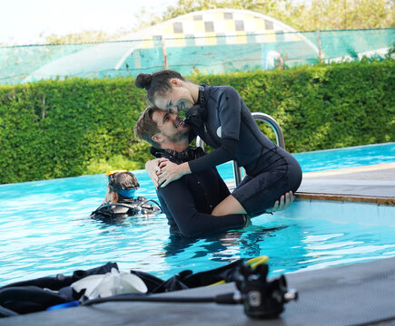 A professional diver and a novice put on fins and diving equipment before dive in a pool.