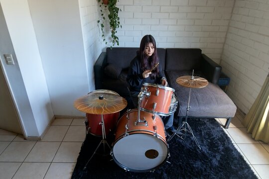 A top down view of a woman practicing on a drum set at home
