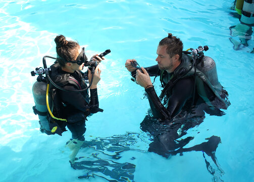 Professional scuba diver instructs the novice how to use the equipment before dive