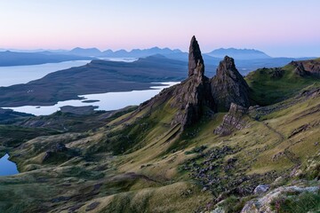 Naklejka premium The Iconic Rock Spire Rising Over Verdant Hills Beneath Distant Peaks
