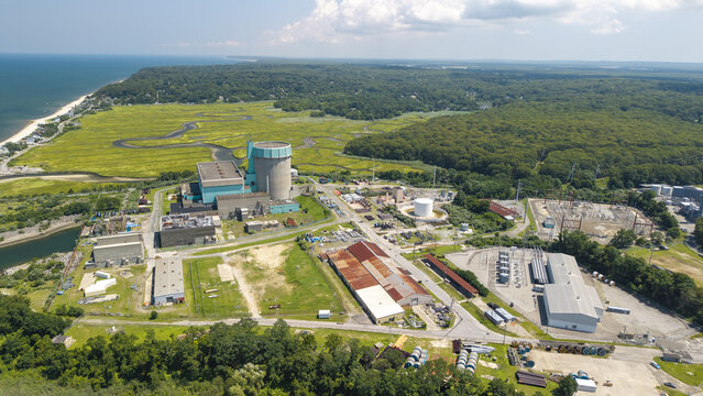 Aerial view of the Shoreham Nuclear Power Plant on Long Island, featuring the containment building and electrical substation surrounded by marshland and forest in New York, United States.