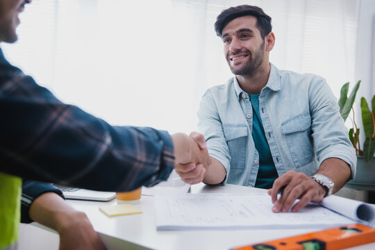 Construction engineer shaking hands with client after project meeting in office