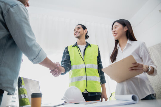 Construction engineer shaking hands with client after project meeting in office