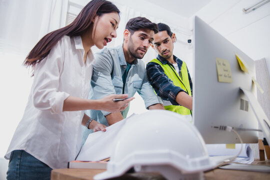 Construction team reviewing project on computer during office meeting