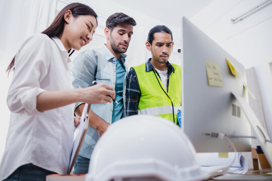 Construction team reviewing project on computer during office meeting