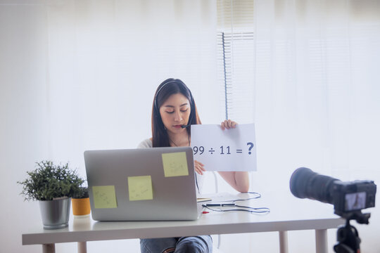 Young woman recording online video lesson with laptop and camera at home studio