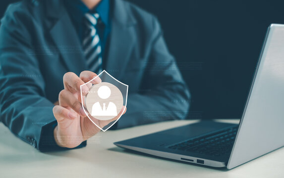 Business professional using a digital shield with a user icon beside a laptop, symbolizing identity protection, data privacy, cybersecurity, secure access, online safety, and trust.
