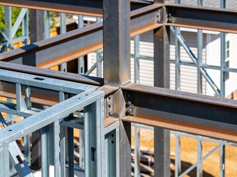 A structural close-up view of a metal building frame with bolted steel beams and light-gauge studs.