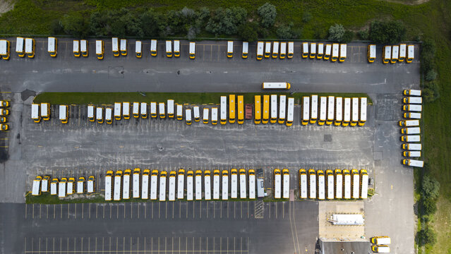 Aerial view of a large parking lot filled with rows of yellow school buses parked in an organized grid pattern at a depot in Middle Island, New York, United States.