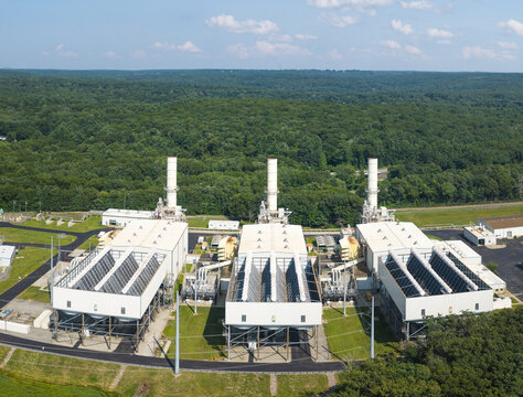 Aerial view of the power plant with three exhaust stacks and industrial buildings, surrounded by dense green forest in Dayville, Killingly, Connecticut, United States.