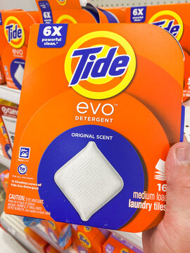 A hand holding a box of Tide Evo laundry detergent tiles on a store shelf - August 8. 2026, Portland Oregon, USA
