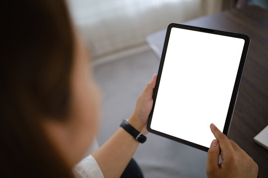 Asian businesswoman holding a tablet with a blank screen for a digital mockup at home.