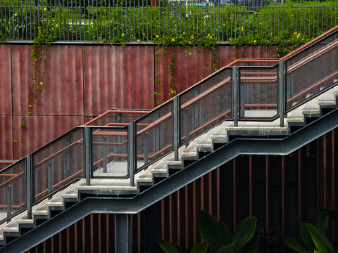 Rusty metal steps beside wall. Exterior staircase with metallic railings and moss