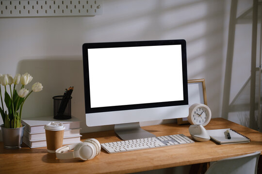 Blank desktop monitor displayed on a modern wooden desk for a digital mockup.