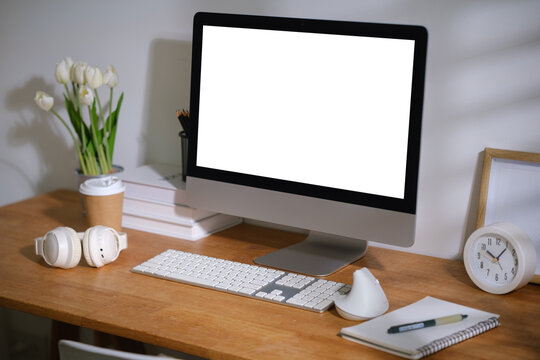 Blank desktop monitor displayed on a modern wooden desk for a digital mockup.