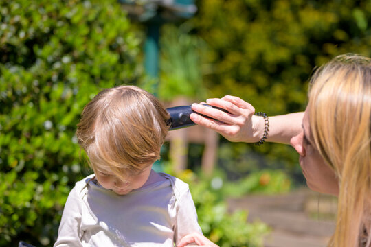 Mother Cutting Toddler Hair Outdoors