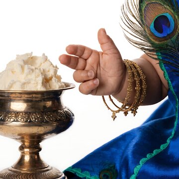 Child hand wearing golden bangles reaching for bowl of fresh white butter during janmashtami celebration with festival celebration janmashtami traditional religion hinduism mythology