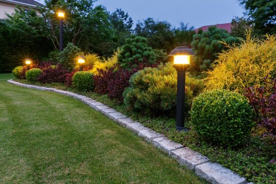The illuminated garden path with warm lamp posts at twilight
