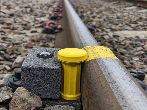 Close-up view of a railway track with a yellow marker on the rail, highlighting infrastructure and transport.
