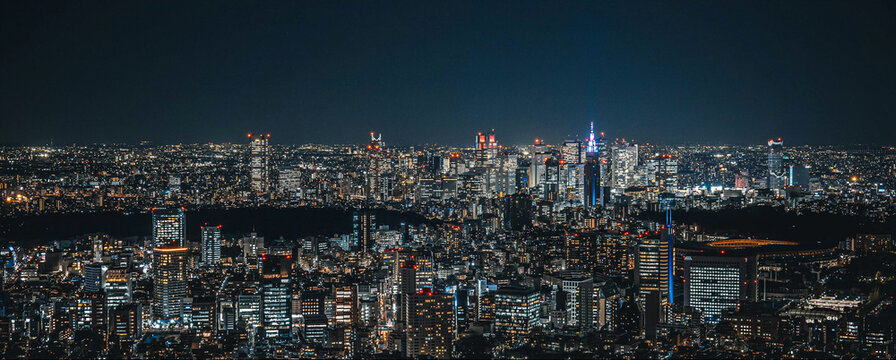 Aerial view of the Tokyo skyline at night, featuring illuminated skyscrapers, dense urban architecture, and glowing city lights in Tokyo, Tokyo, Japan.