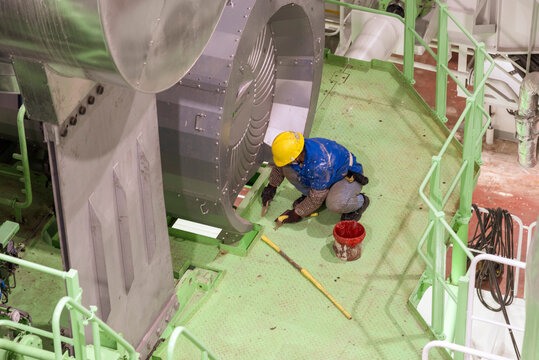 Shipyard worker engaged in painting and cleaning operations inside a newly built ship, contributing to the final finishing work.