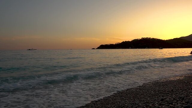 The setting sun casts golden light on the seashore of a tropical resort