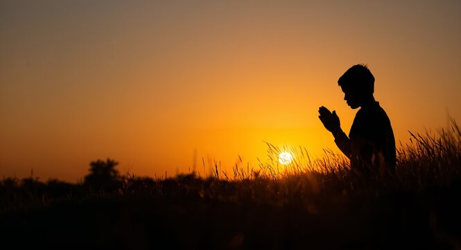 Boy praying at sunset depicted in silhouette illustrating faith hope and peaceful reflection in a serene outdoor environment. concept as A boy praying at sunset depicted in silhouette illustrating fai