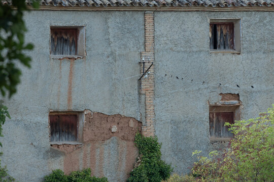 Casa rural antigua con ventanas de madera y p&aacute;jaros sobre un cable