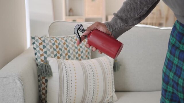 Person Spraying Fabric Refresher on Sofa Cushions