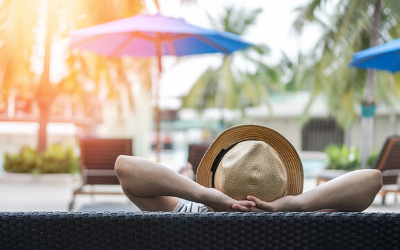 Summer resort hotel stay relaxation of business woman take it easy happily resting on beach chair on holiday travel vacation poolside in peacefully with tropical beach swimming pool