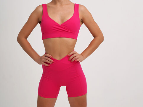 Athletic woman wearing bright pink sports bra and fitted workout shorts 