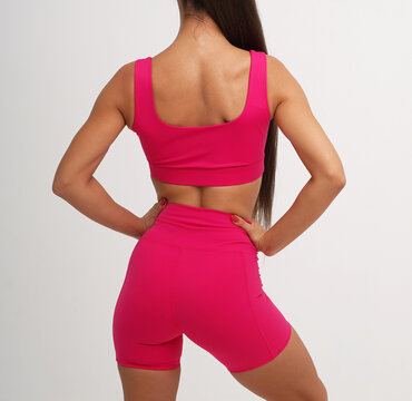 Athletic woman wearing bright pink sports bra and fitted workout shorts 
