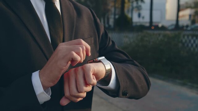 Businessman raises hand and looks at the smartwatch on it. Businessman is typing message on the smartwatch.  Modern gadgets and people concept. Modern communication. Close up, slow motion footage.