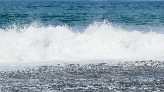 Blue sea and large waves and foam. Wave splashing over pebbles at sea. Rolling ocean waves. Summer beach background. Powerful sea waves	