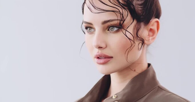 Close-up face of a girl with bright fashionable make-up. Beautiful young woman  with stylish hairstyle posing at studio. Sexy girl with green eyes. Fashion model with beautiful eyes. Real time