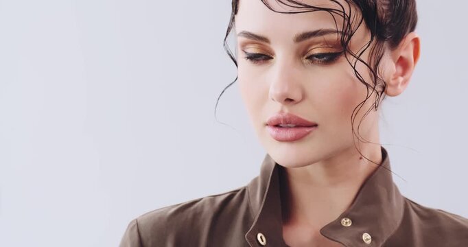 Close-up face of a girl with bright fashionable make-up. Beautiful young woman  with stylish hairstyle posing at studio. Sexy girl with green eyes. Fashion model with beautiful eyes. Real time