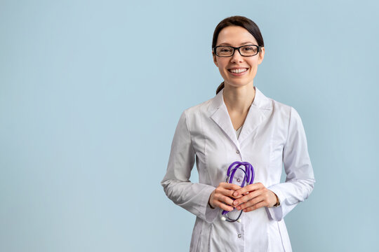Female doctor holding stethoscope and smiling on blue background