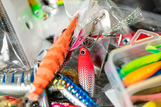 Orange squid jig and colorful metal fishing lures in tackle box The Concept of sea angling and squid fishing
