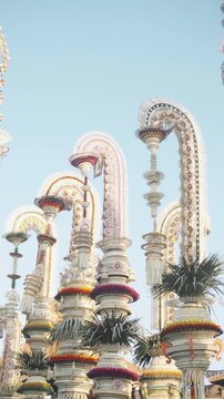 Wide Cluster of White Dominant Penjor Arches with Colorful Petal Bases and Lontar Symbol &mdash; Bali Hindu Galungan Street Scene