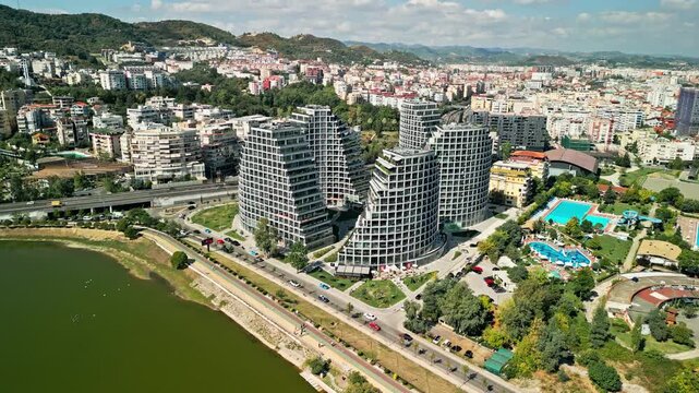 Albania, Tirana 06 09 2025: Aerial drone video descending smoothly from high angle to side view of Lake View Residences with artificial lake in foreground.