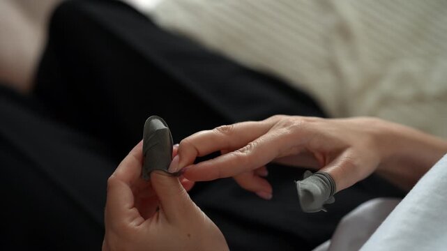 Young female gamer putting on professional gaming finger sleeves, preparing for mobile esports competition, ensuring smooth gameplay on smartphone touchscreen without friction, closeup, slow motion.