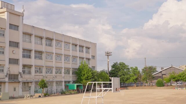 柔らかい光に包まれる夕暮れ時の校舎と背後で湧き上がる大きな入道雲