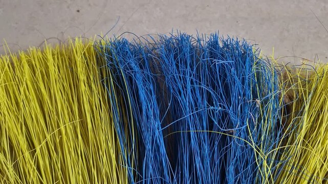 Panning close-up shot of yellow and blue plastic broom bristles background texture