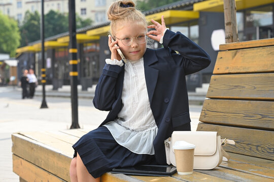 A little girl, elegantly dressed in a business suit, smiles at the camera