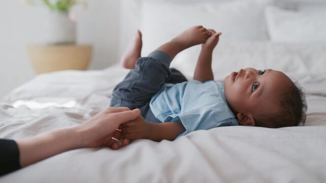 Start life and explore world, little baby boy lying in bed and looking around. Cute infant with big black eyes examining room, mother love and tenderness, happy family moments, carefree childhood