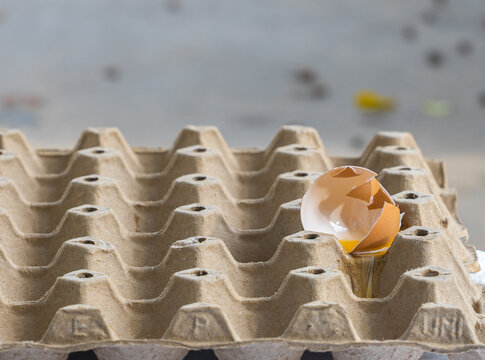 Broken Raw Egg Spilling onto a Cardboard Egg Tray