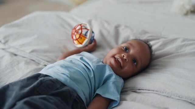 Portrait of cute african american baby, boy or girl lying in bed and smiling. Charming little child enjoying life and exploring world, positive emotions and good mood, carefree childhood moments